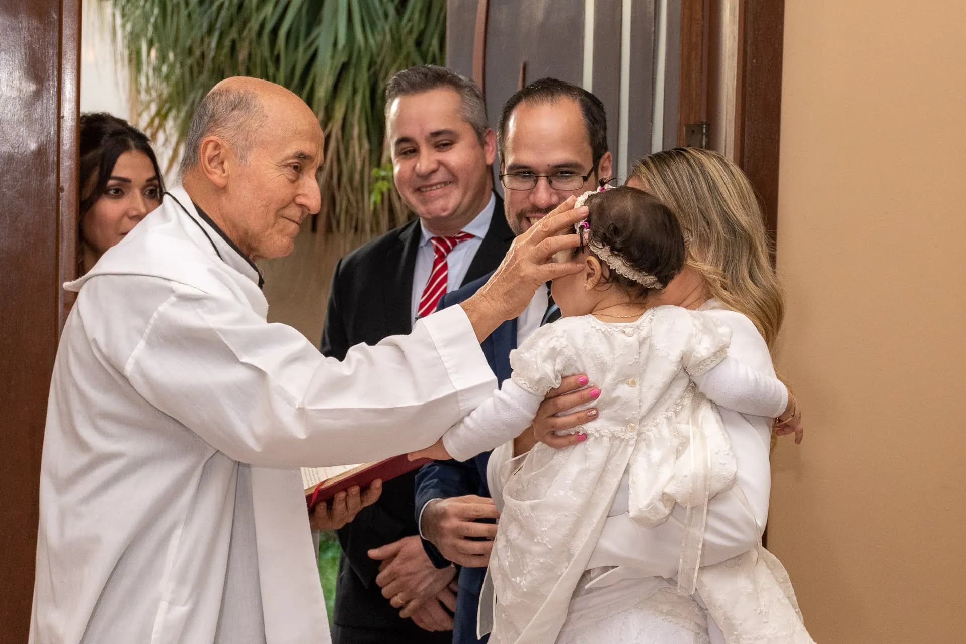El sacerdote bendiciendo a la niña durante el bautismo
