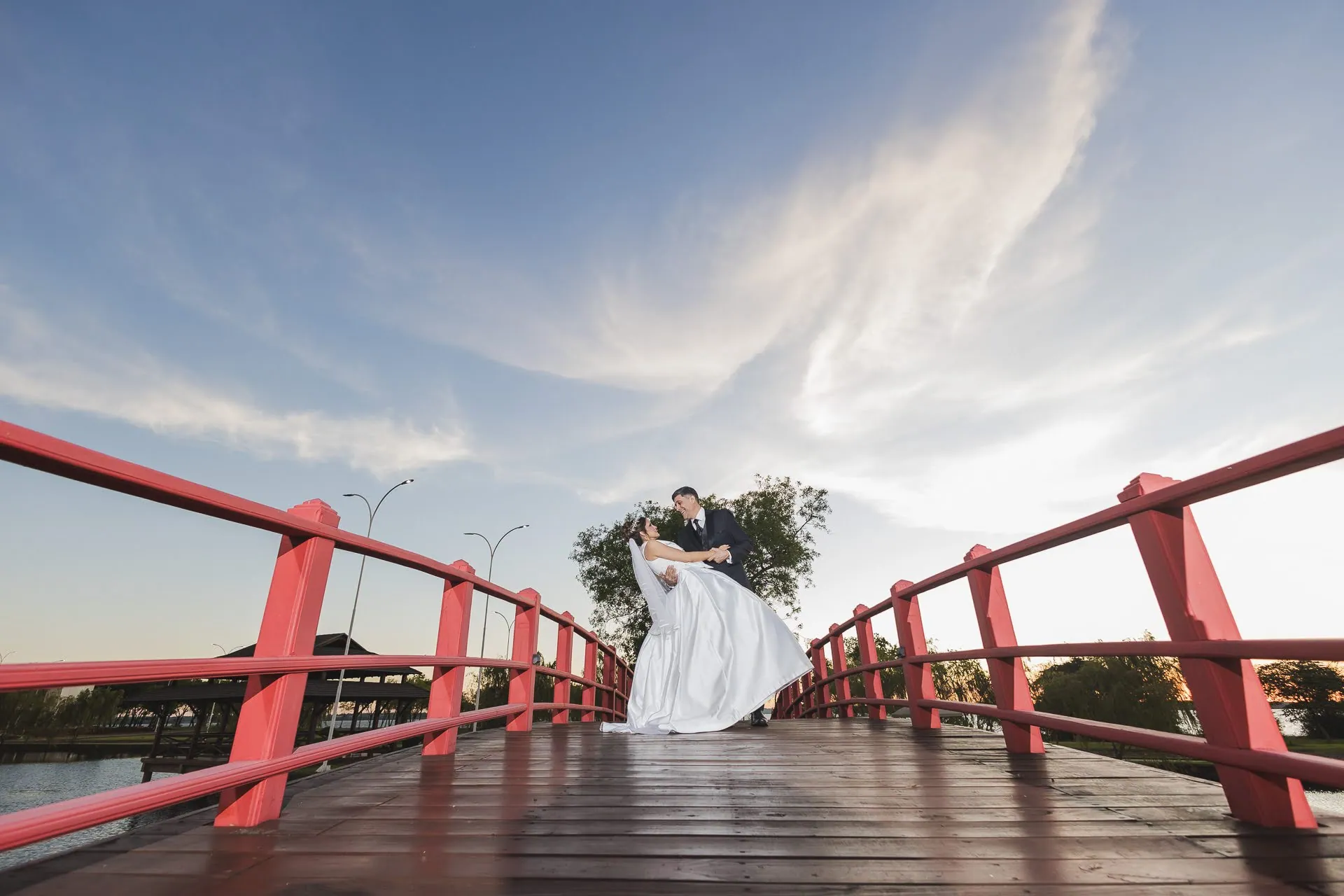 Los novios sobre un puente rojo al atardecer