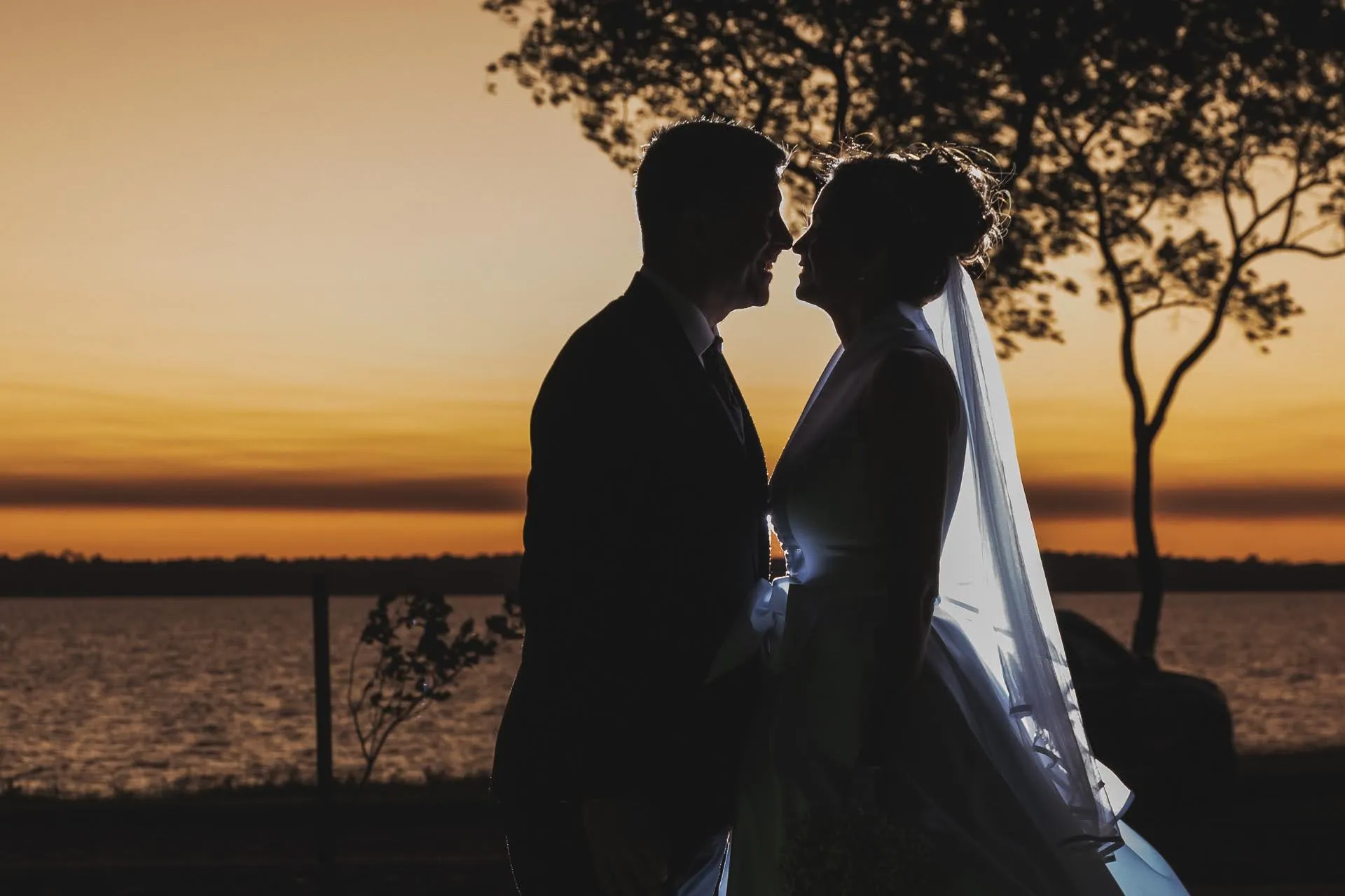 Siluetas de los novios frente al lago
